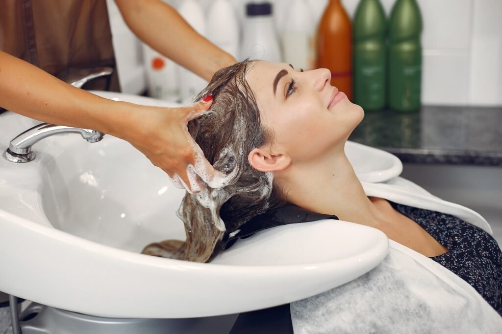 Hairdresser washing head her client. Woman in a hair salon